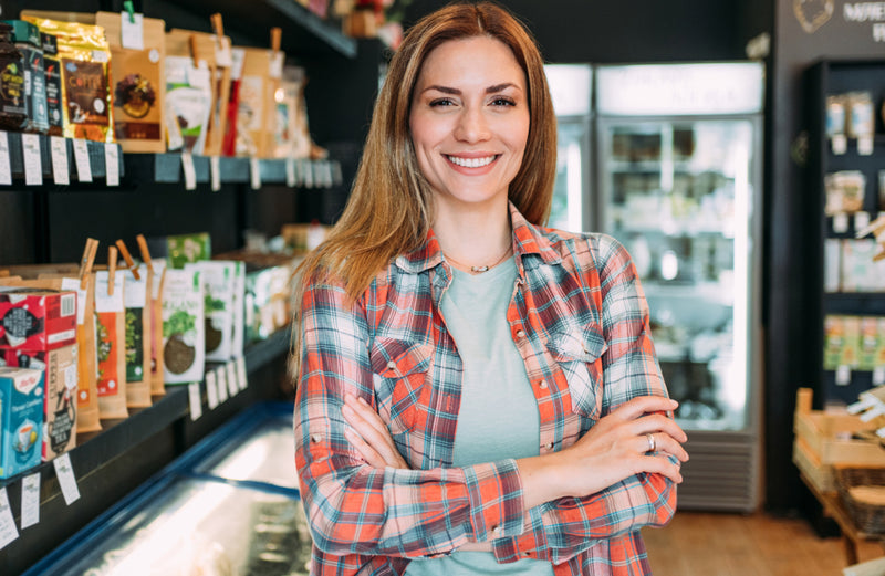Woman standing in a store with arms crossed, wearing a plaid shirt.